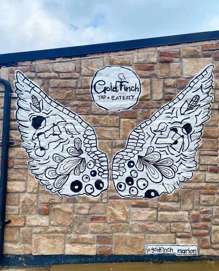 Black and white wings mural on a brick wall with 