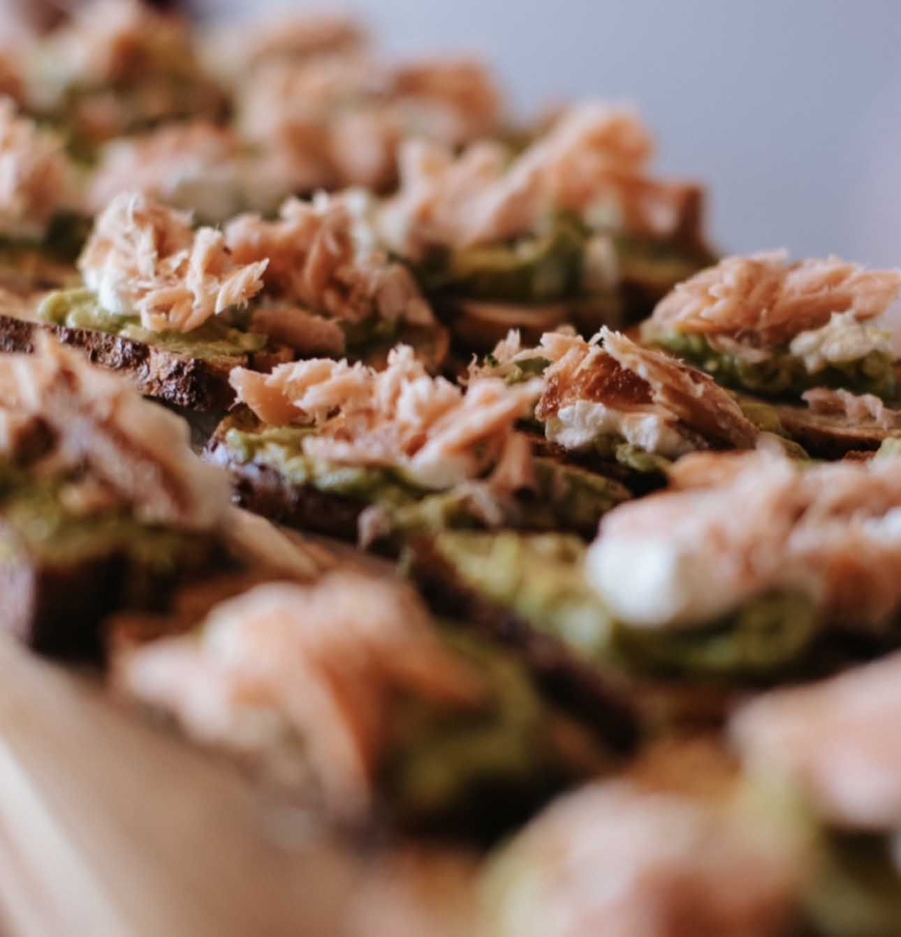 Toasted bread topped with avocado, cheese, and shredded salmon.