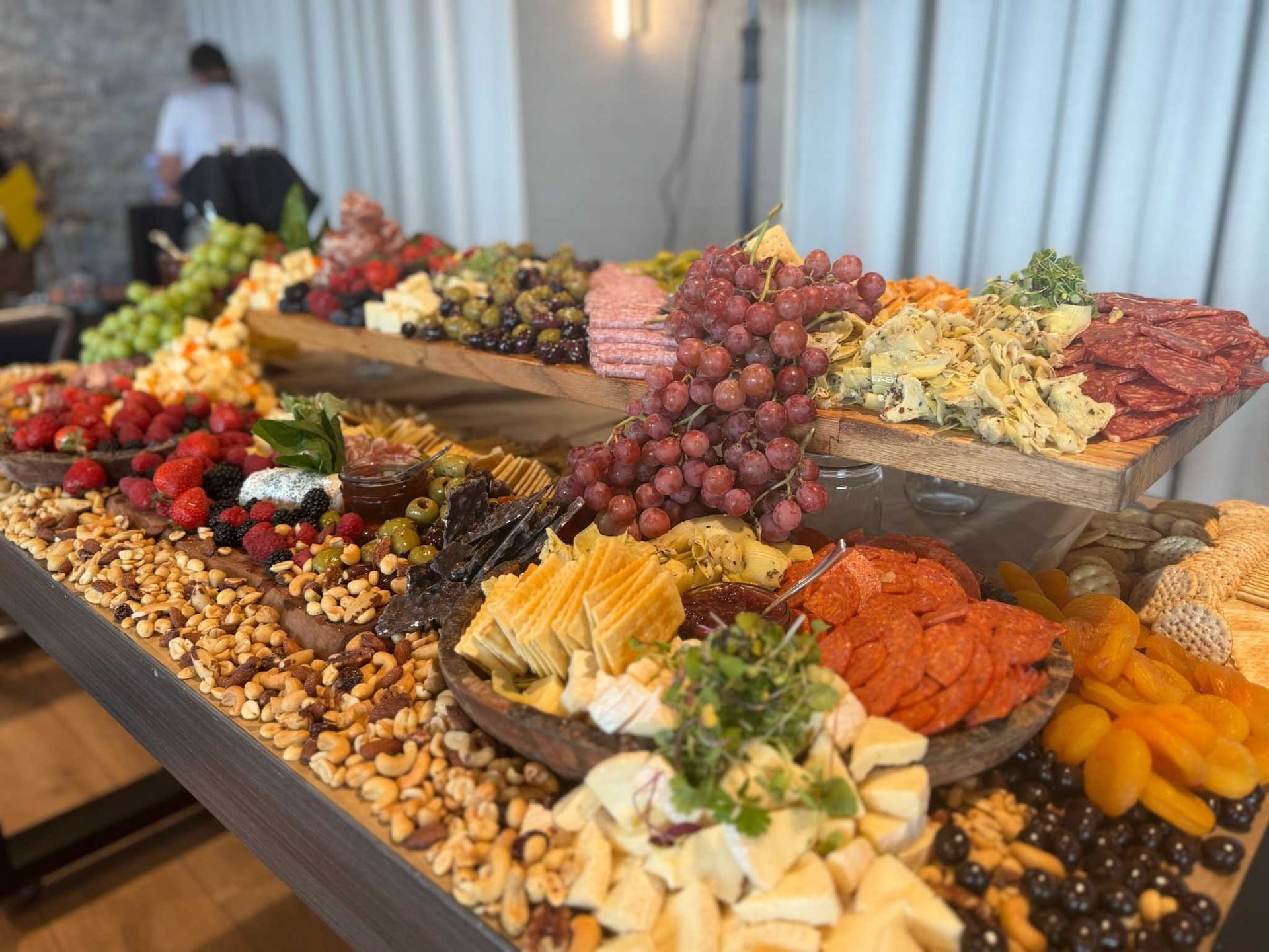 A large charcuterie board overflowing with various cheeses, fruits, meats, and nuts.