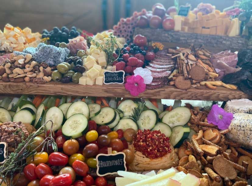 Charcuterie board with various cheeses, fruits, vegetables, crackers, and meats.