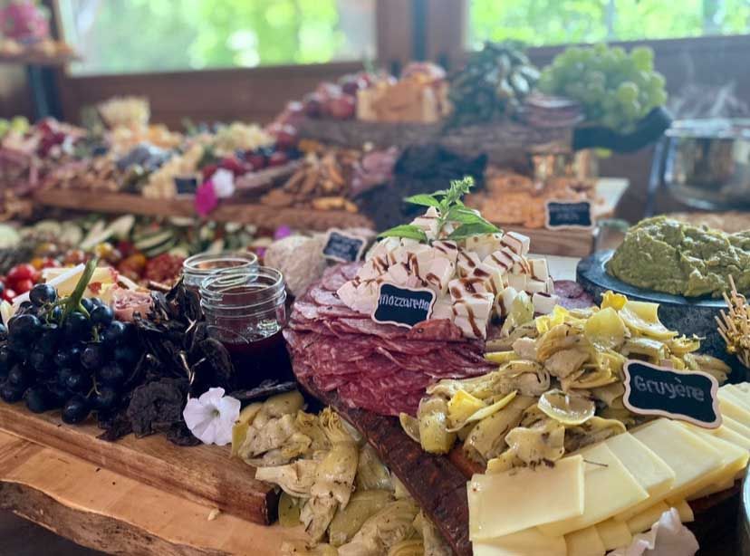 Charcuterie board with salami, cheese, artichokes, grapes, and other food items.