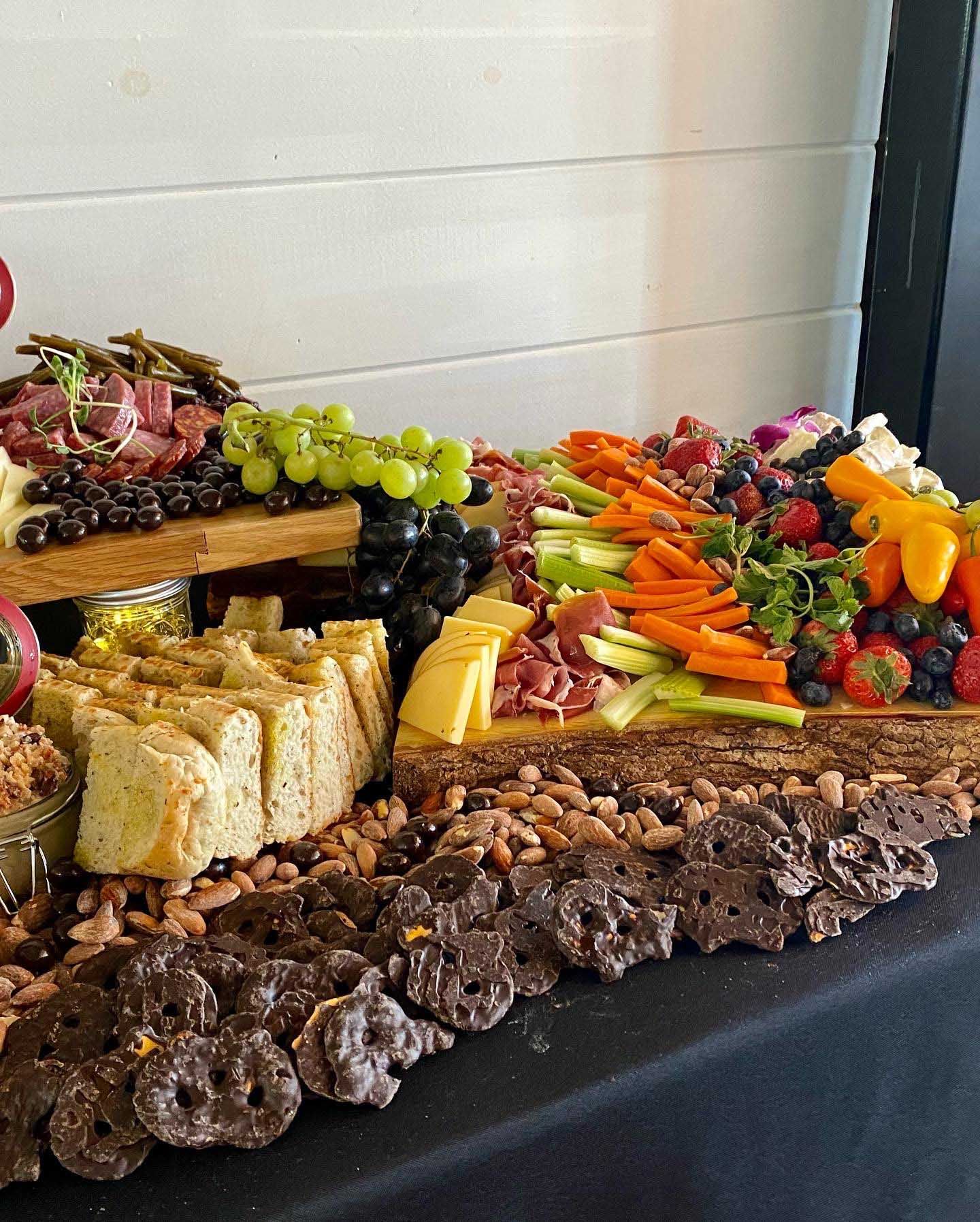 Charcuterie board with various cheeses, meats, fruits, and vegetables.