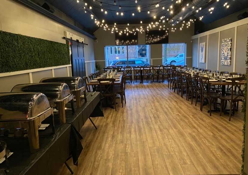 Restaurant dining area with buffet tables, rows of tables, and string lights.