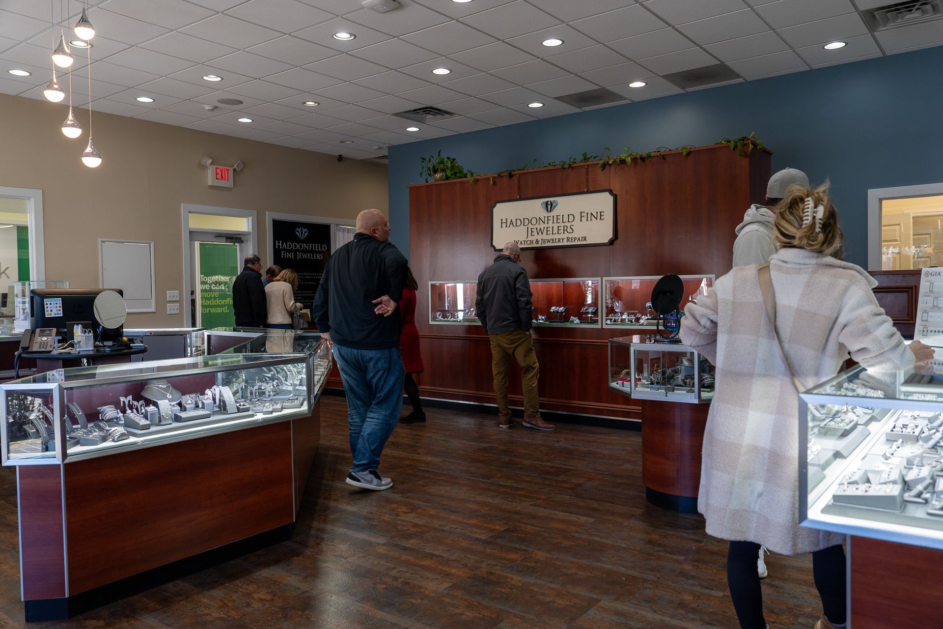 Jewelry store interior with glass display cases and customers browsing the counter.