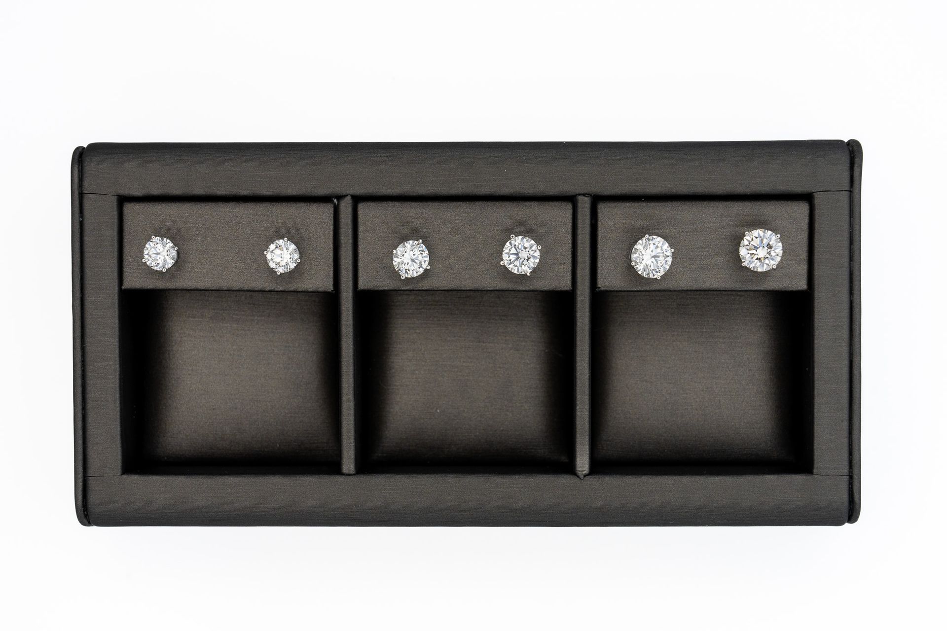 Black three-switch wall panel with silver screw heads on a white background.