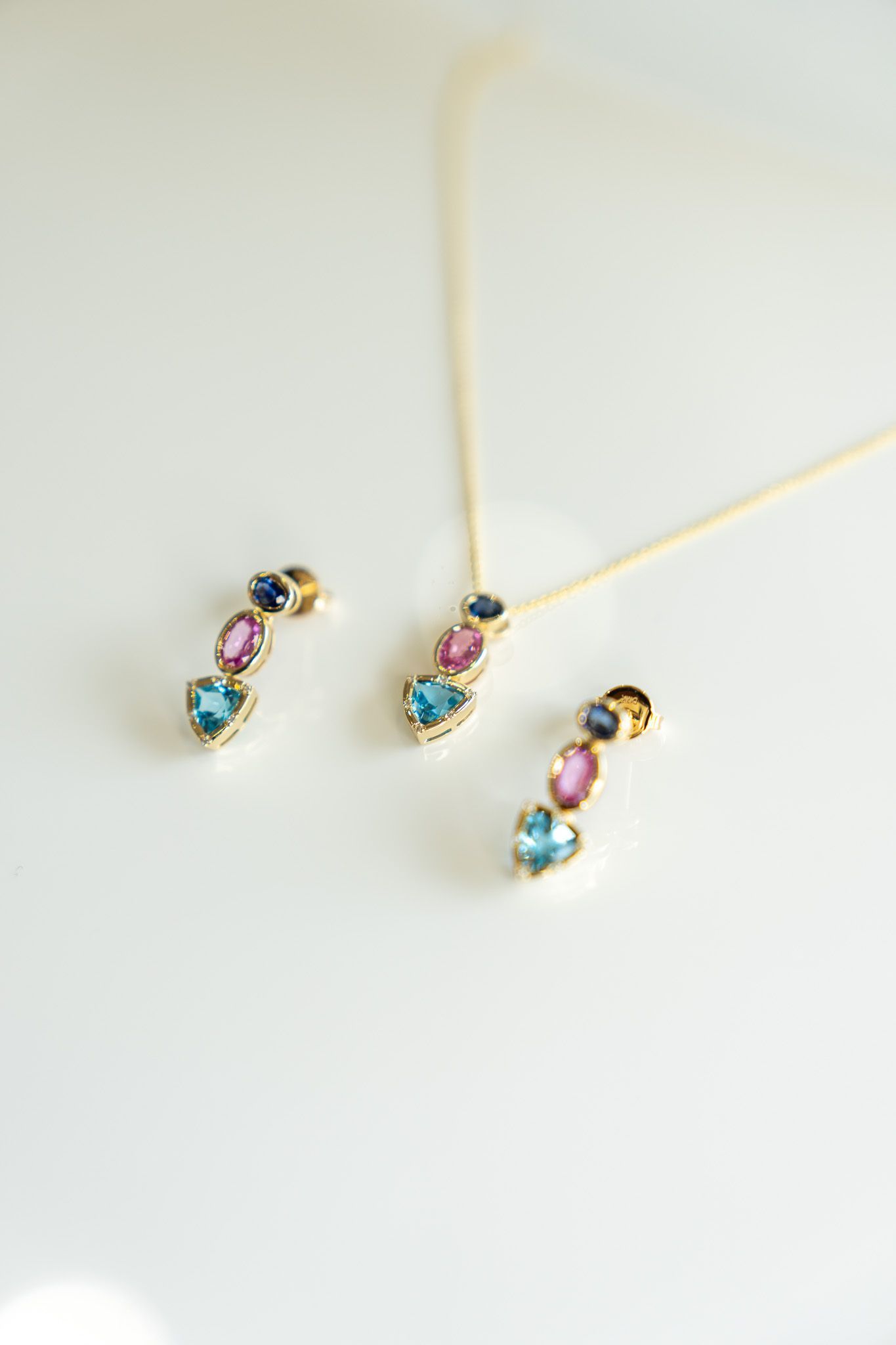 Three small gemstone pendant necklaces with gold chains on a white background.