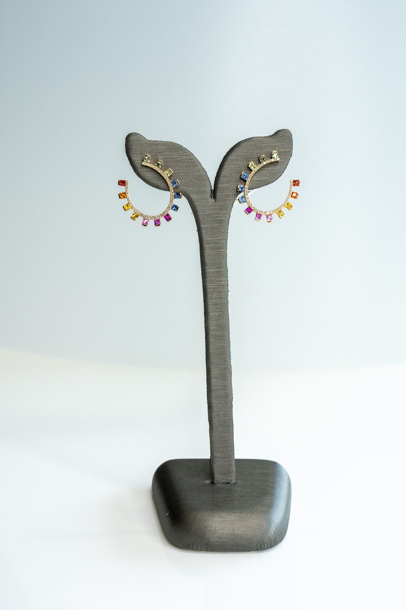 Decorative jewelry stand with two leaf-shaped earrings on a black base.