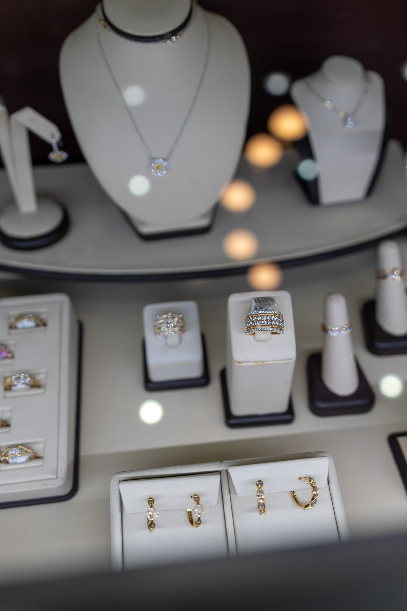 Jewelry display with silver necklaces and rings in black cases under bright lights.
