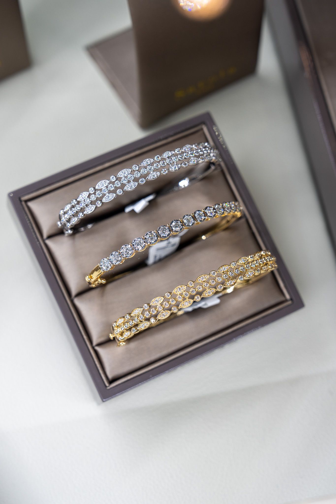 Three decorative jeweled hair clips in a display tray, silver and gold tones.