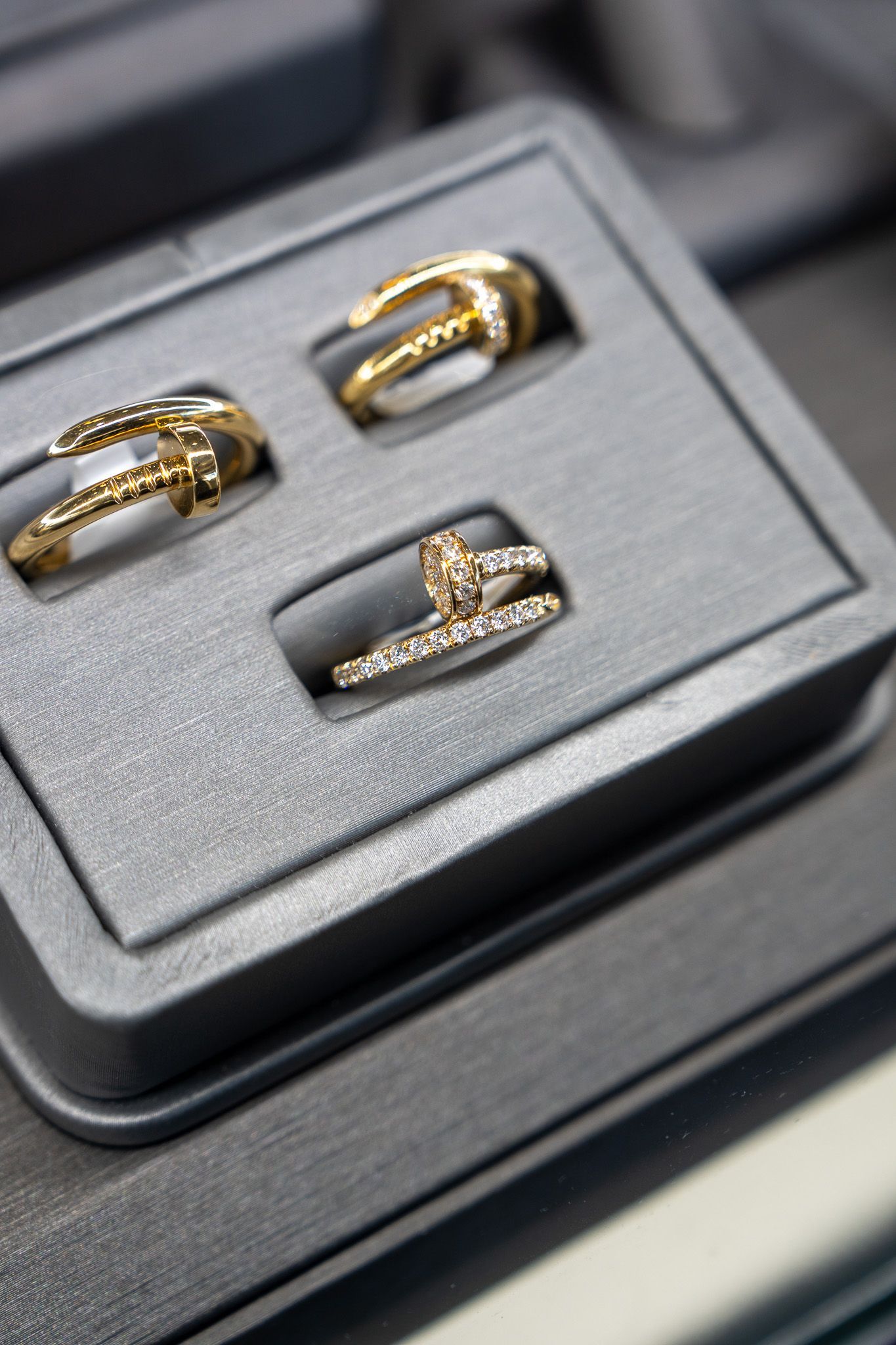 Three gold rings with gemstones displayed in a black jewelry box.