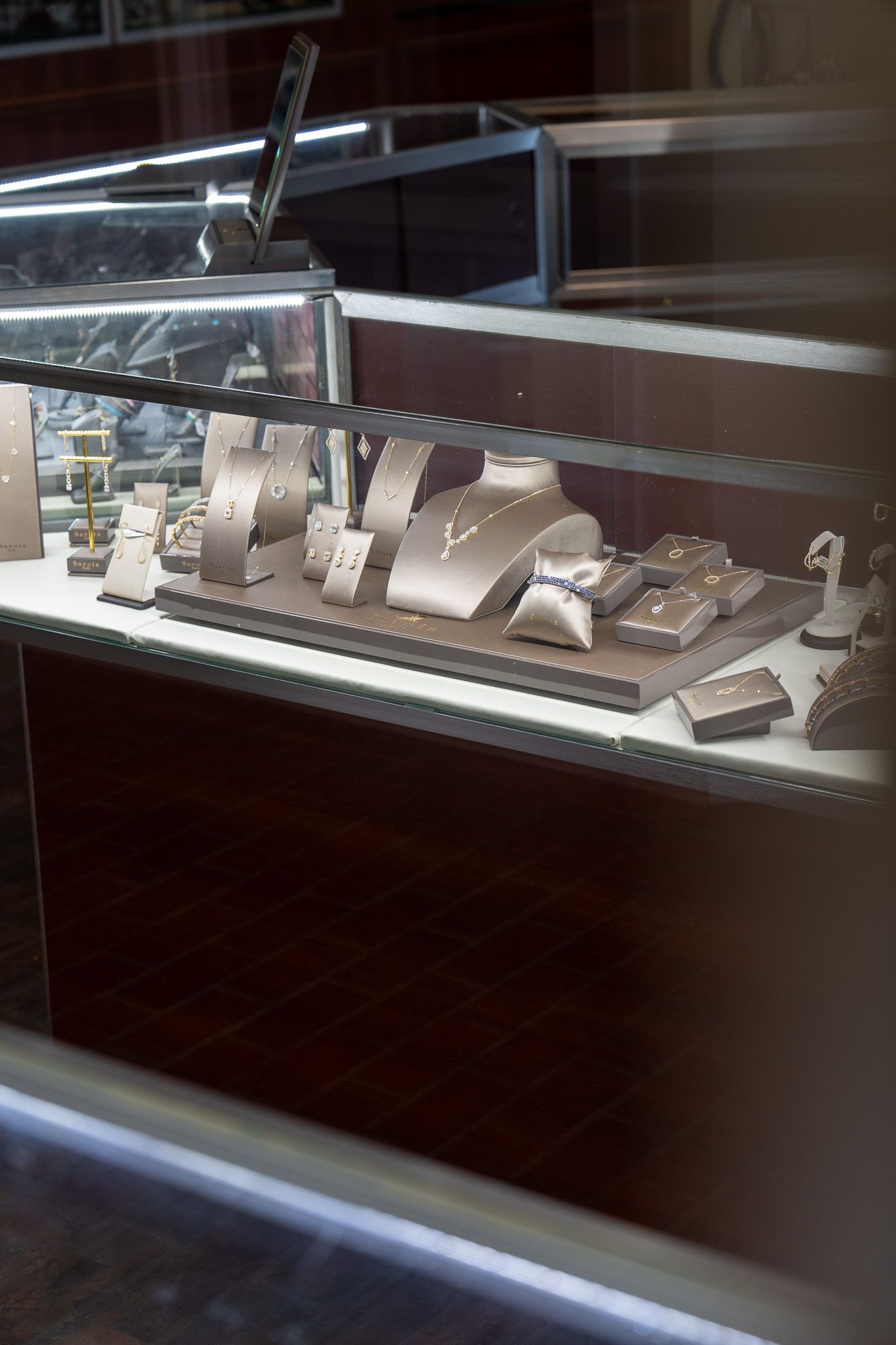 Glass display case with small white architectural models and objects arranged on shelves.