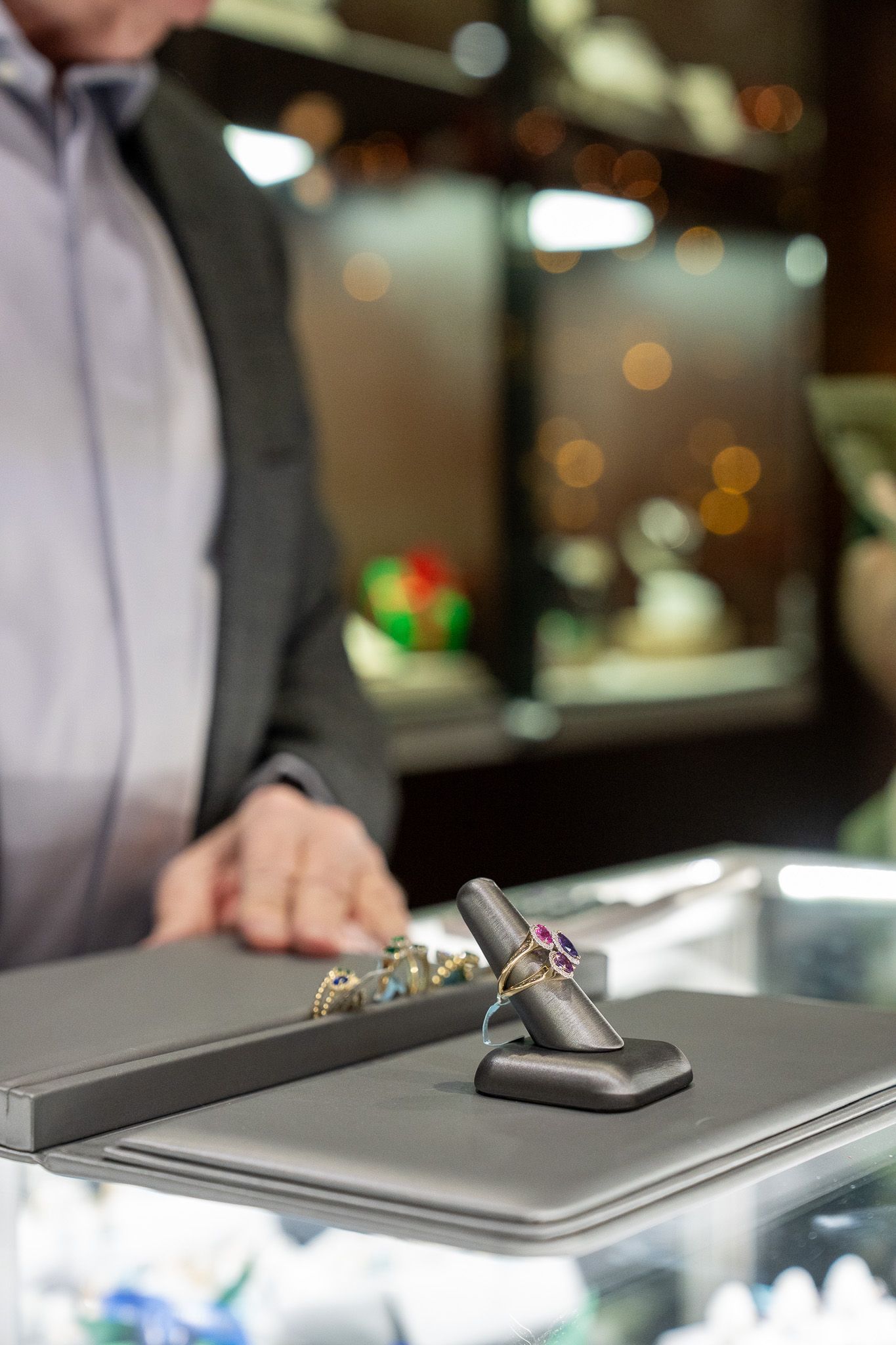 Person presenting a black smartphone on a glass display counter in a store.