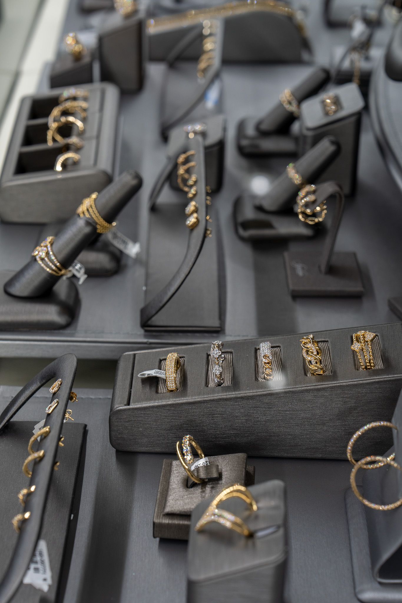 Black velvet jewelry display with gold rings and earrings arranged in trays.