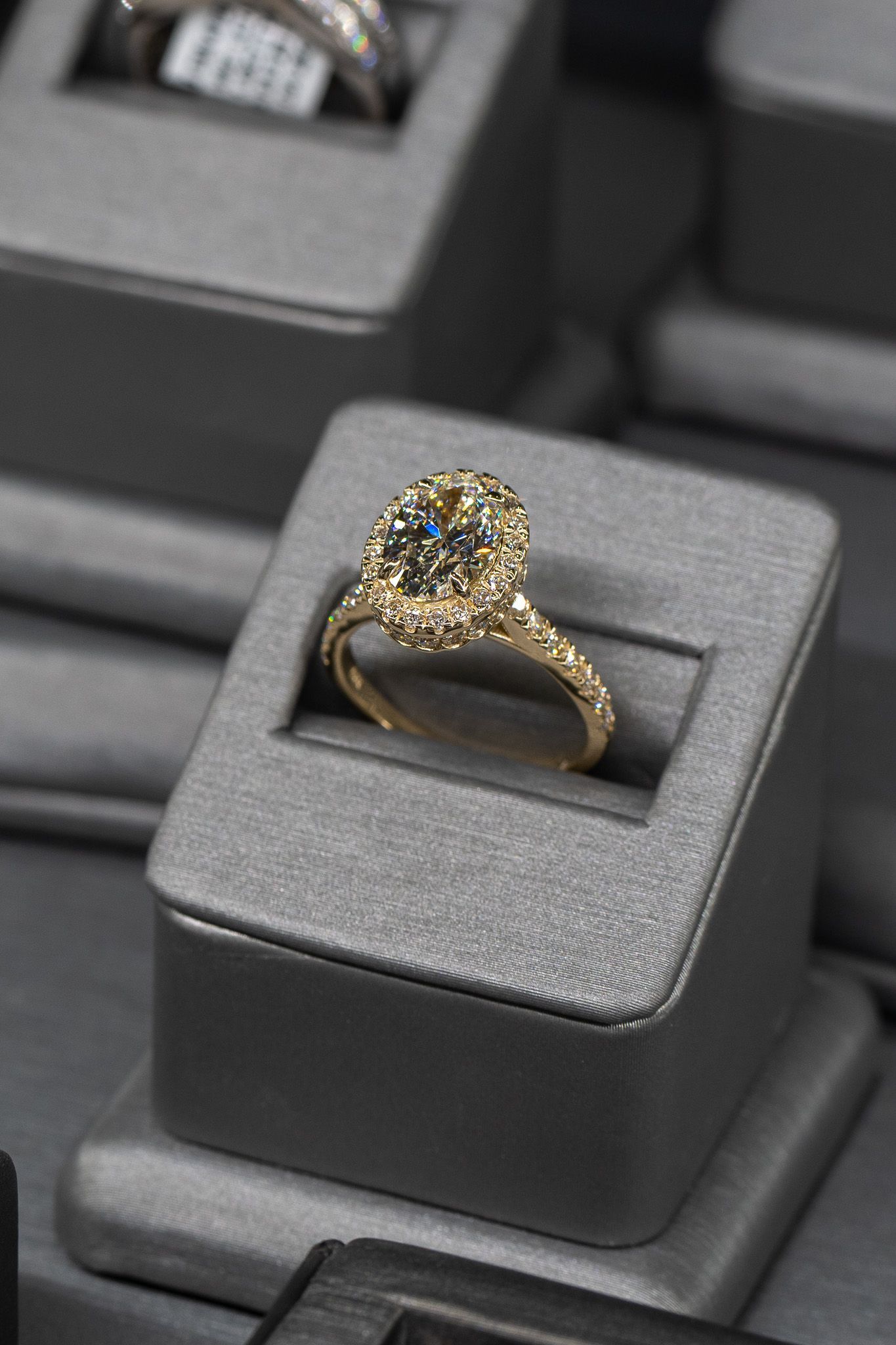 Gold ring with a cluster of dark gemstones displayed on a gray jewelry stand.