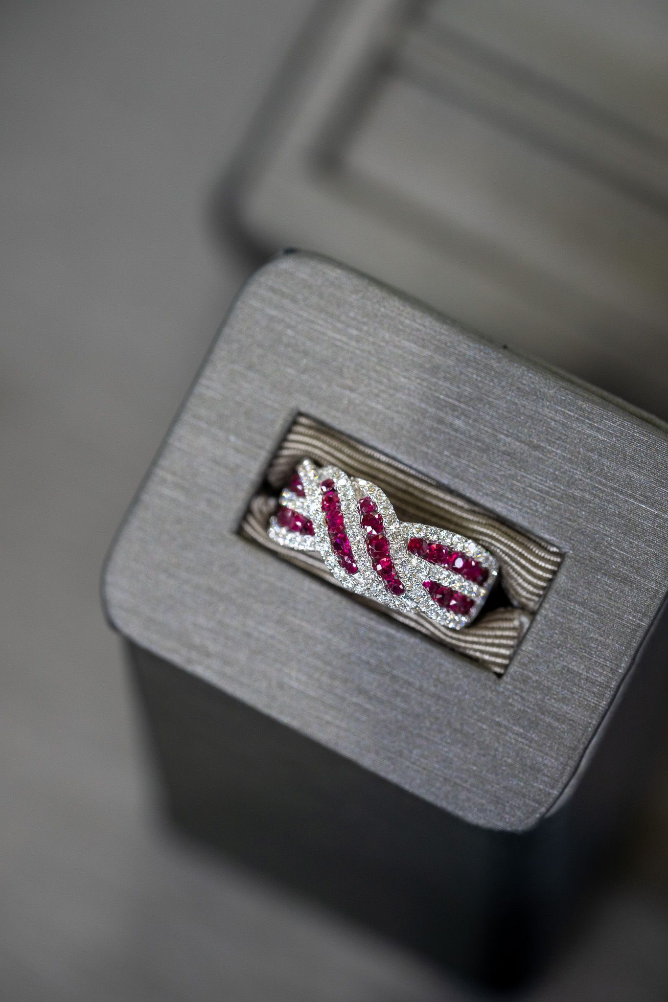 Close-up of a metallic keycap with red-and-white stitched fabric inset on a blurred keyboard or device surface.