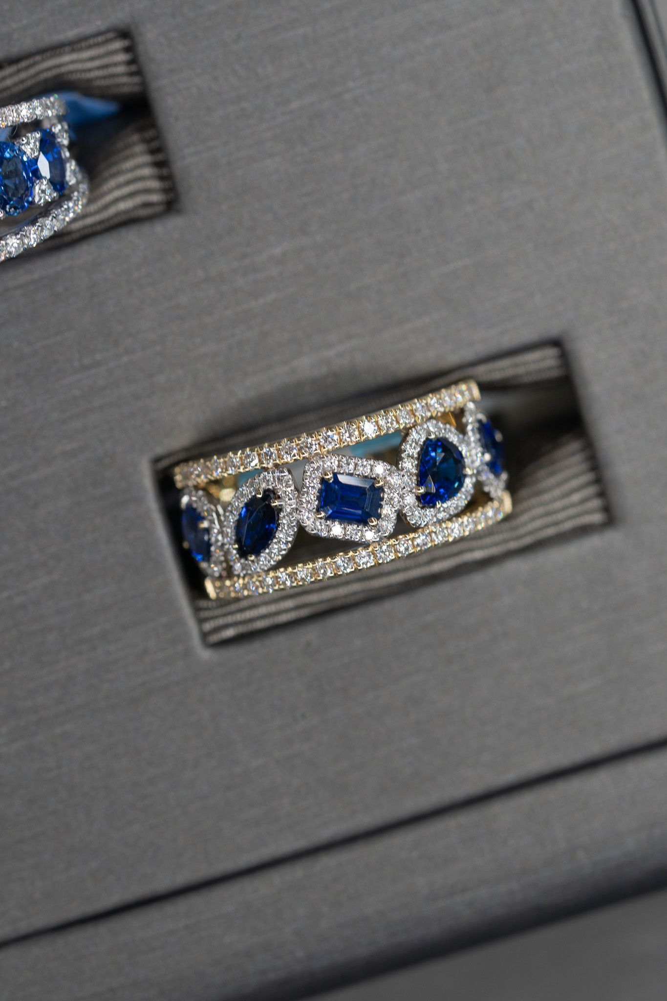Close-up of a gray box with a silver ring set with blue stones.