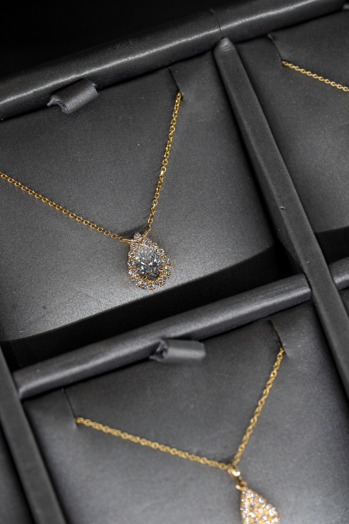 Gold necklaces with gemstone pendants displayed in black jewelry boxes.