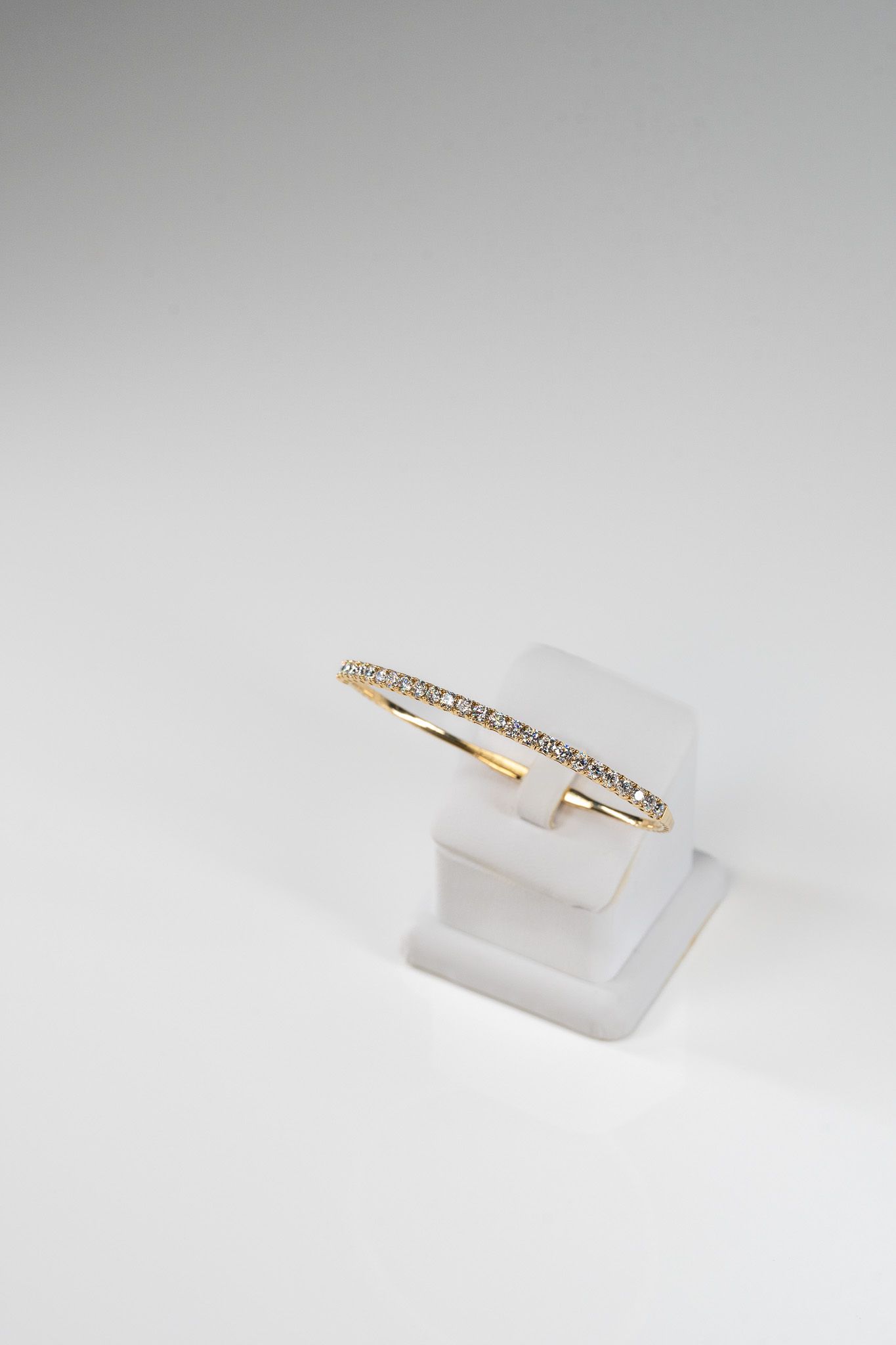 Gold and white ring displayed on a clear stand against a white background.