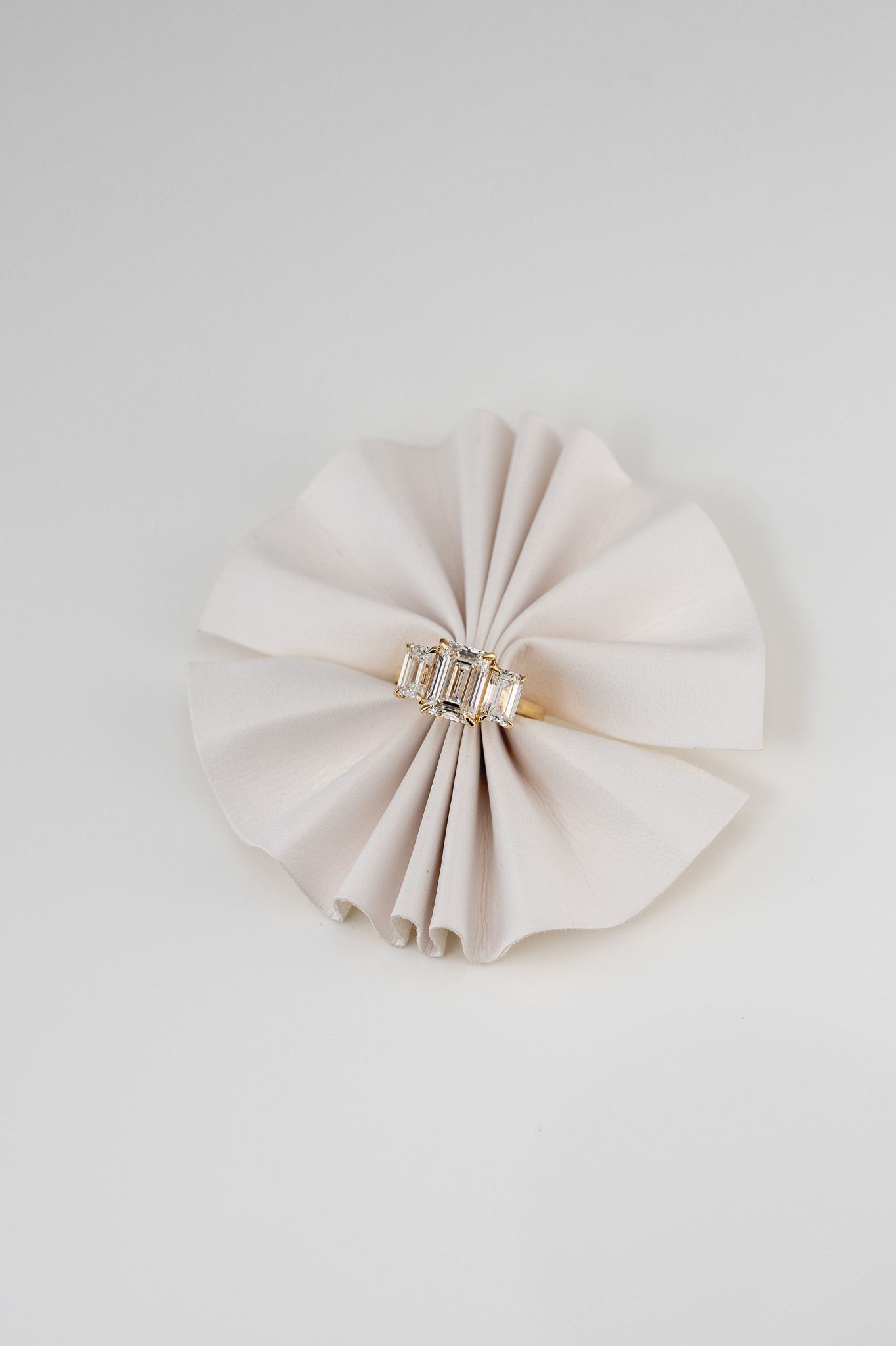 White pleated paper rosette with a small gold beaded center on a light background.