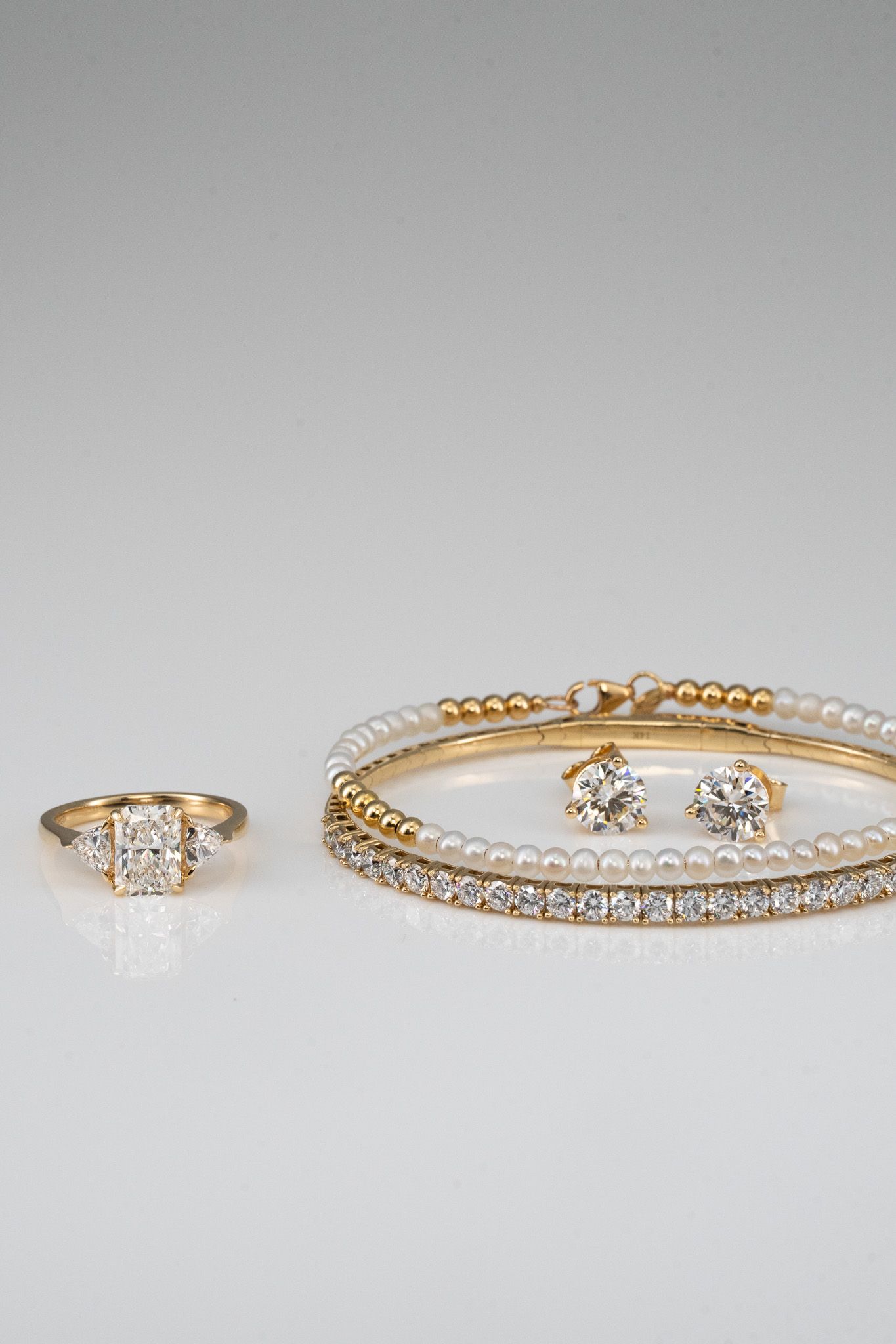 Gold and diamond rings displayed on a light gray surface