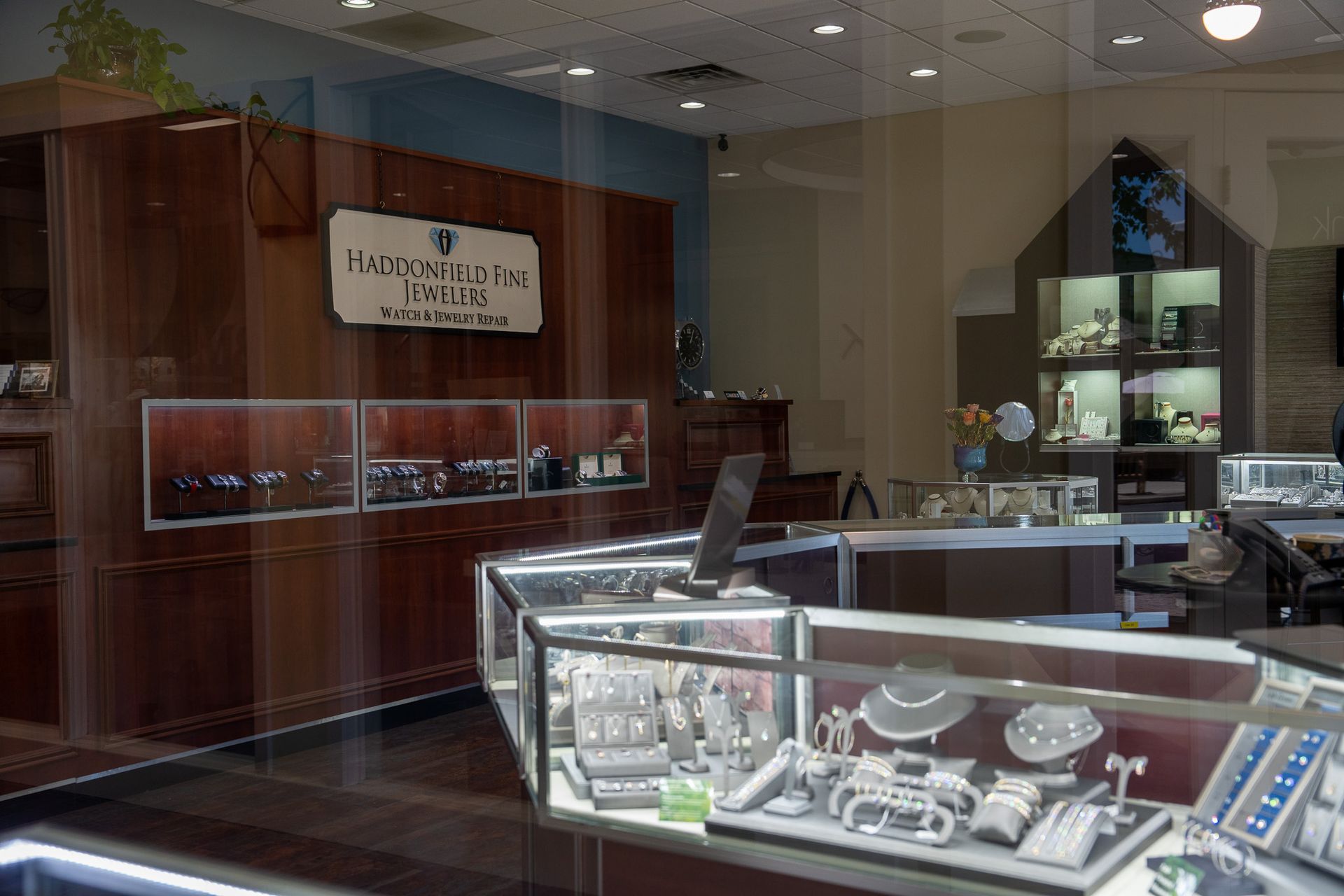 Jewelry store interior with glass display cases, wood panels, and wall-mounted shelves.