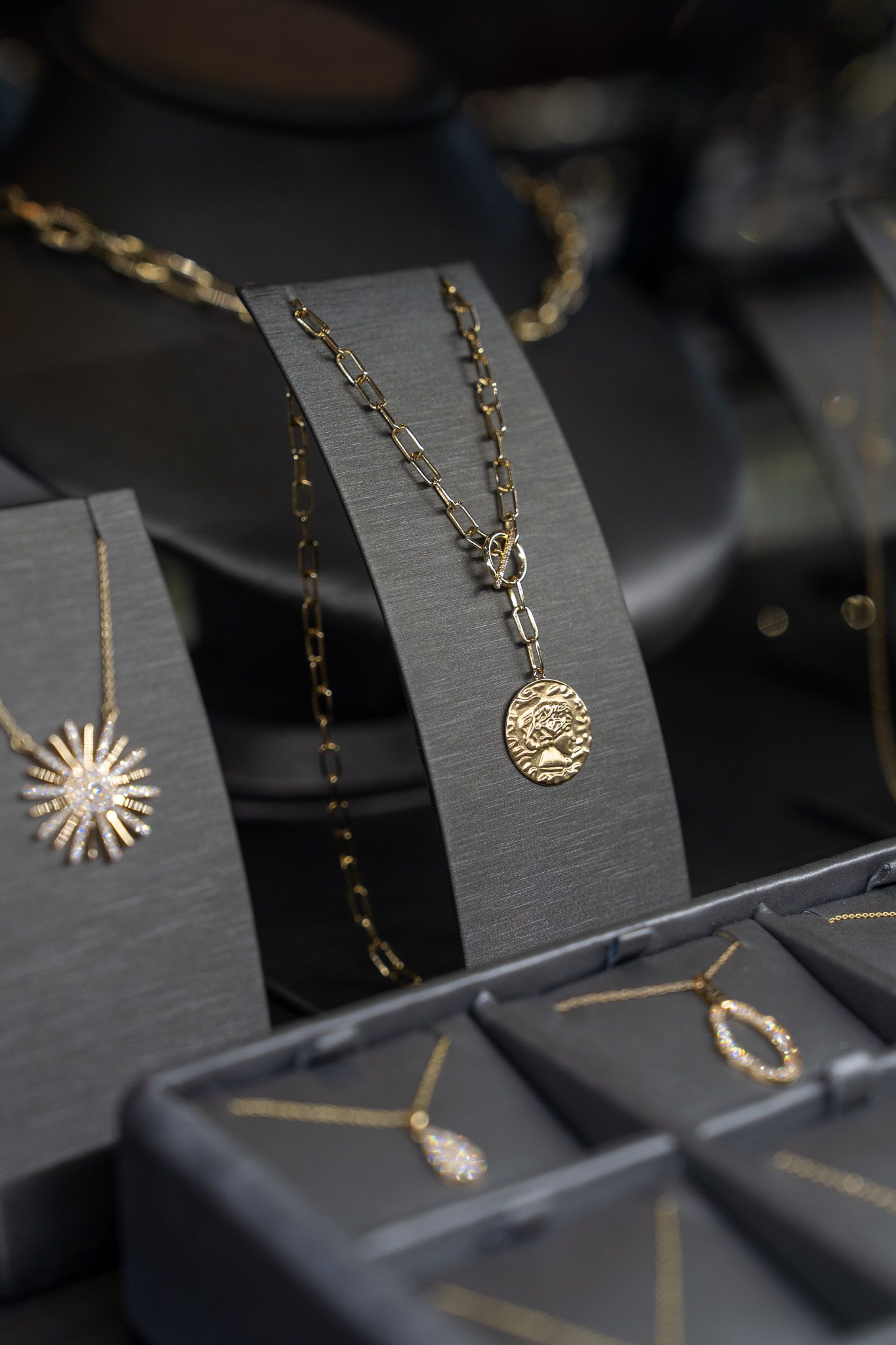 Gold necklaces and pendants displayed on black velvet jewelry stands and trays.