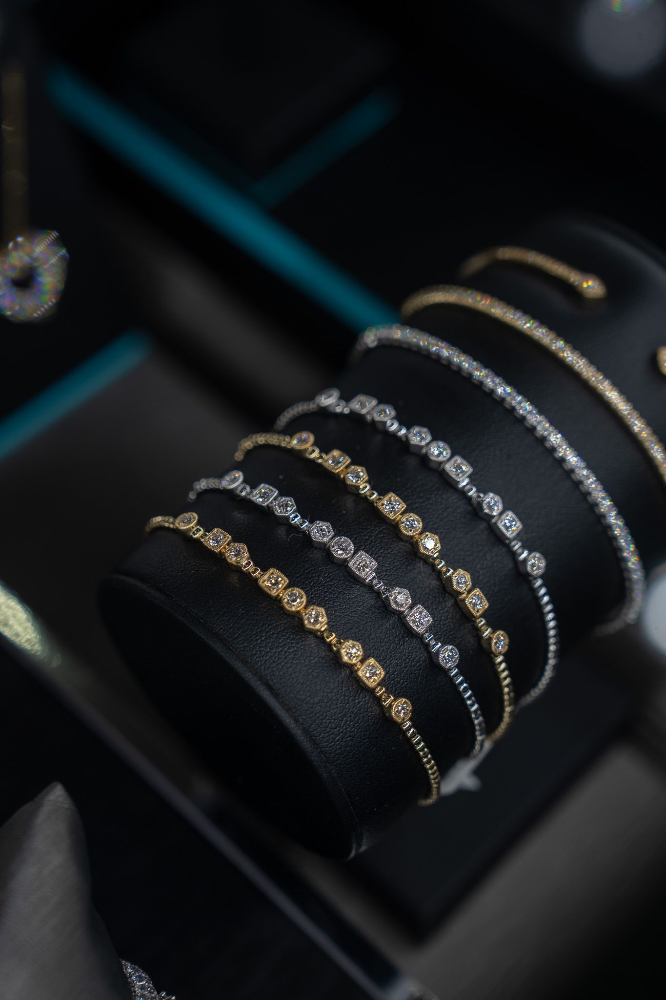 Bracelets with black, silver, and gold chains displayed on a dark velvet jewelry stand