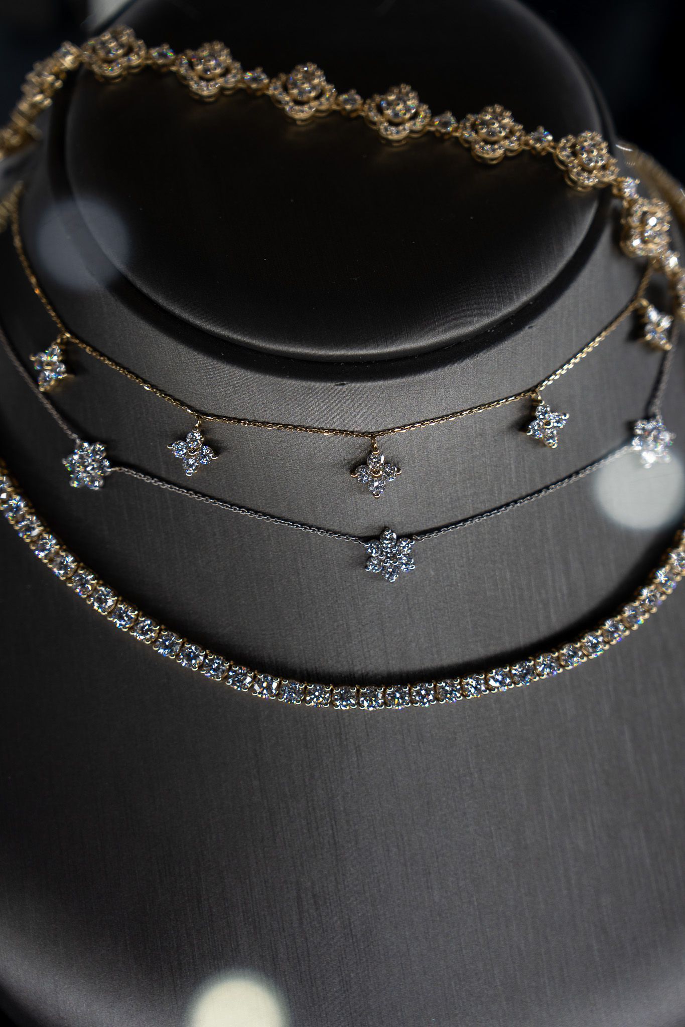 Stacked gold and silver beaded necklaces displayed on a black jewelry stand.