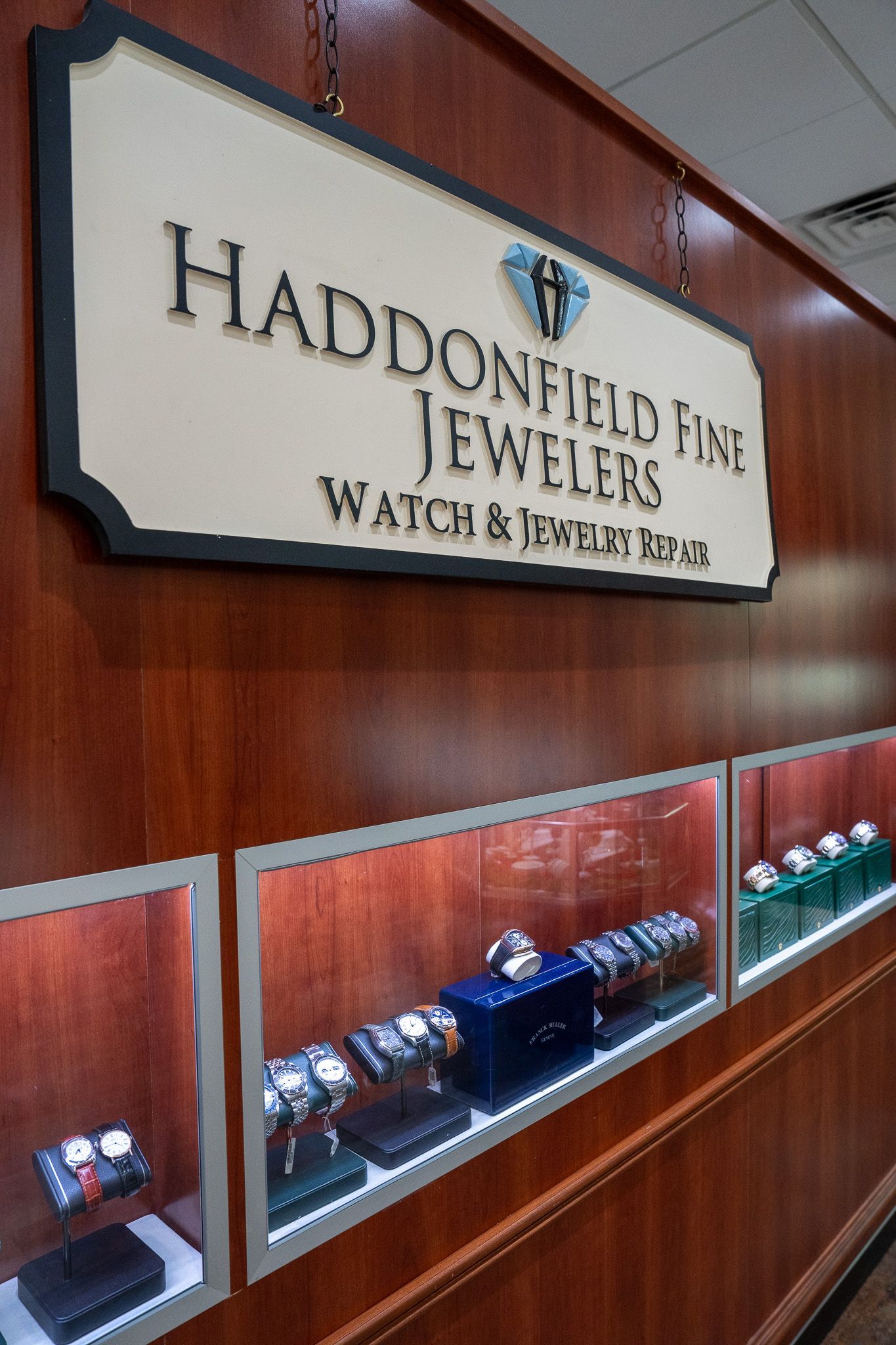 Jewelry store wall display with sign reading “Handcrafted Fine Jewelry” and glass cases below