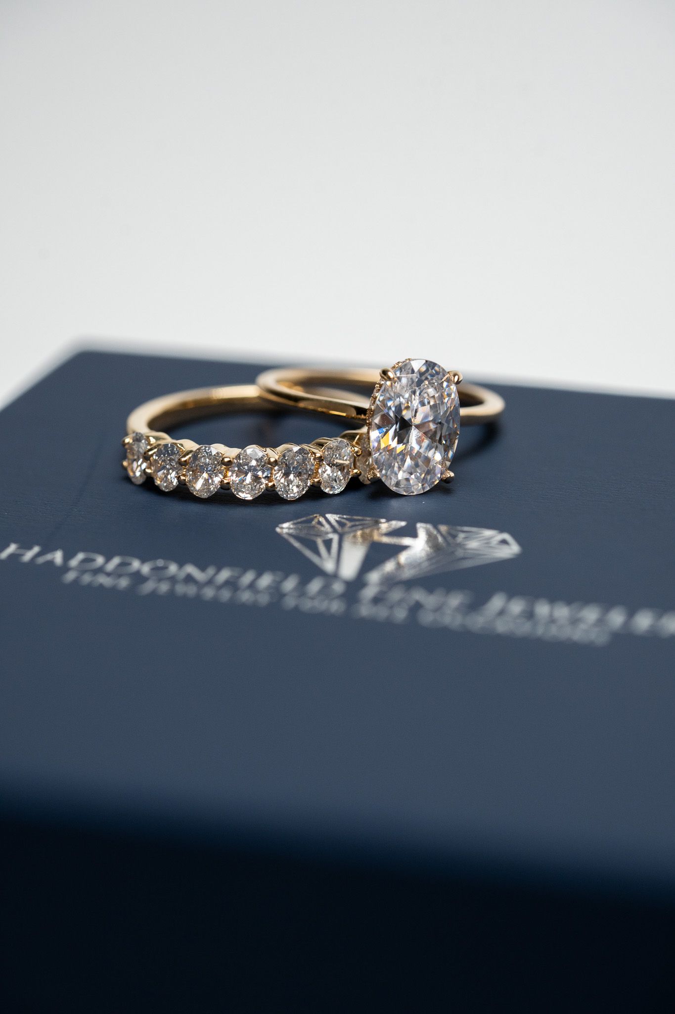 Two gold rings with diamonds on a dark blue jewelry box