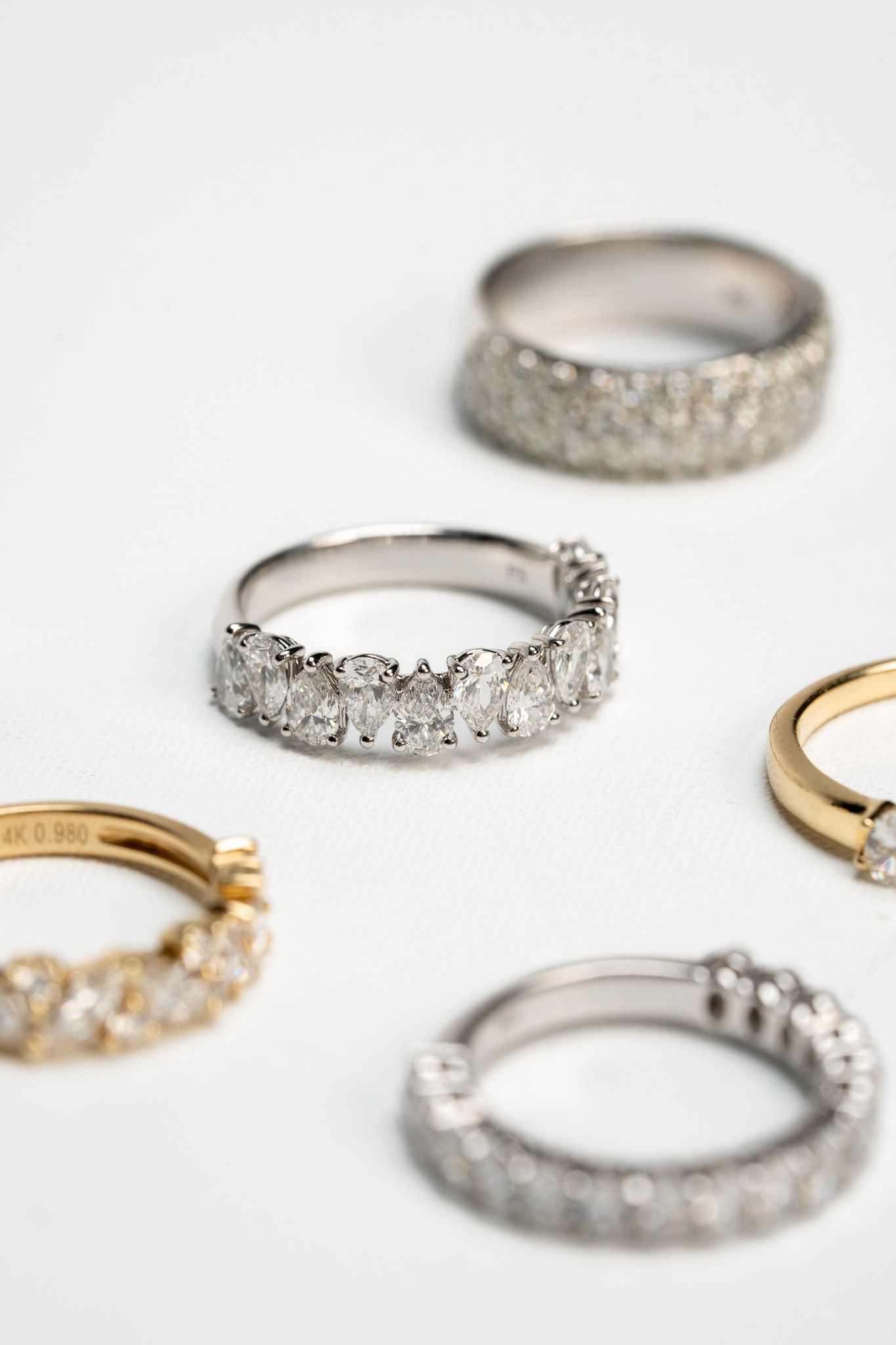 Assorted silver and gold diamond-studded rings on a white surface