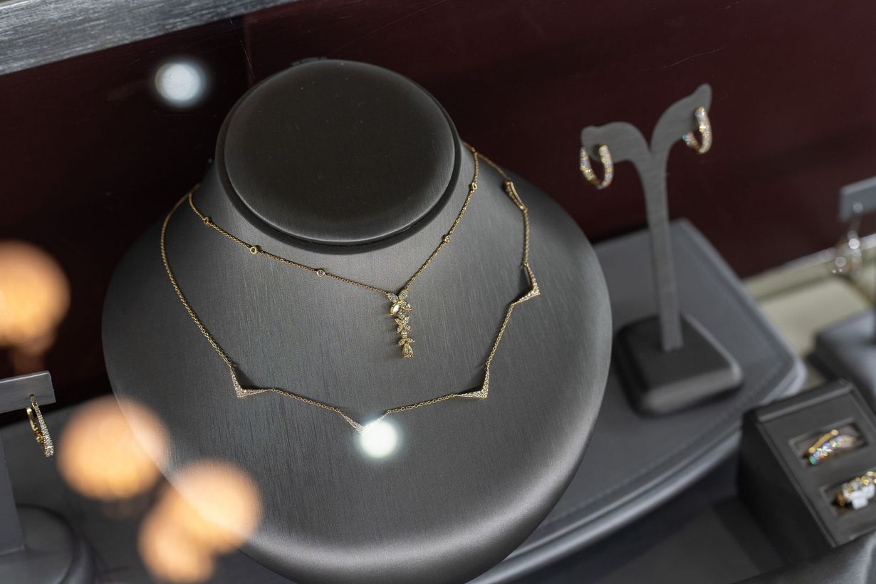 Gold necklace displayed on a black bust stand with matching jewelry displays nearby.