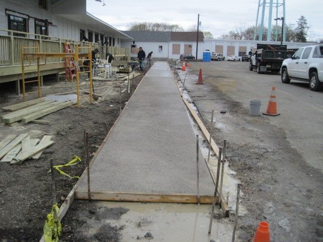 A concrete walkway is being built near a parking lot