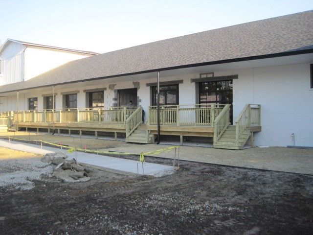 A white building with a wooden deck and stairs