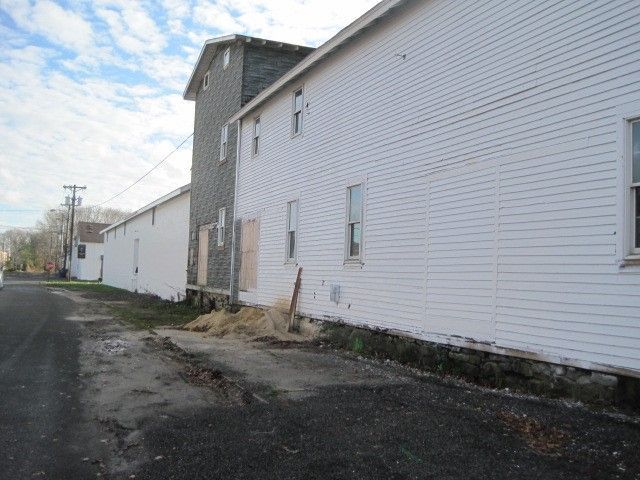 A white building with a lot of windows is sitting on the side of a road.