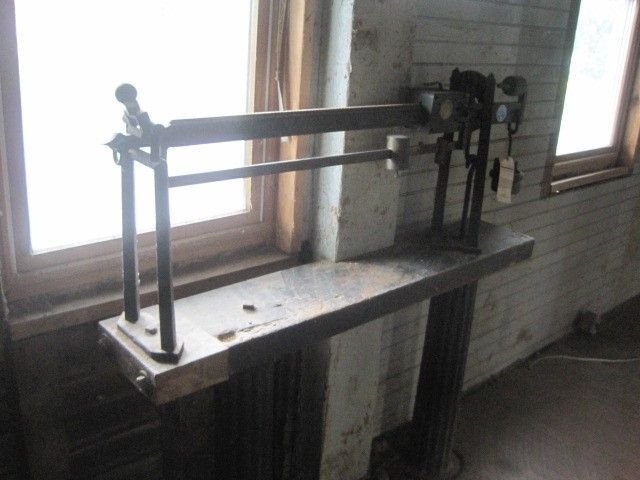 An old scale is sitting on a wooden table in front of a window