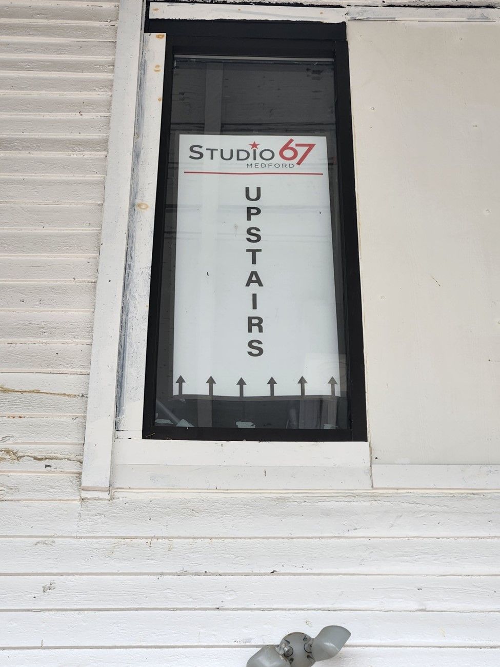 A sign that says studio 67 upstairs on it