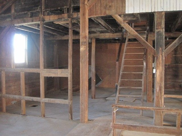 An empty room with wooden beams and a ladder