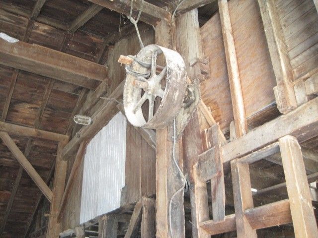 A large wheel is hanging from the ceiling of a wooden building.