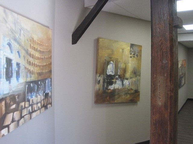 A hallway with two paintings on the wall and a wooden pole.