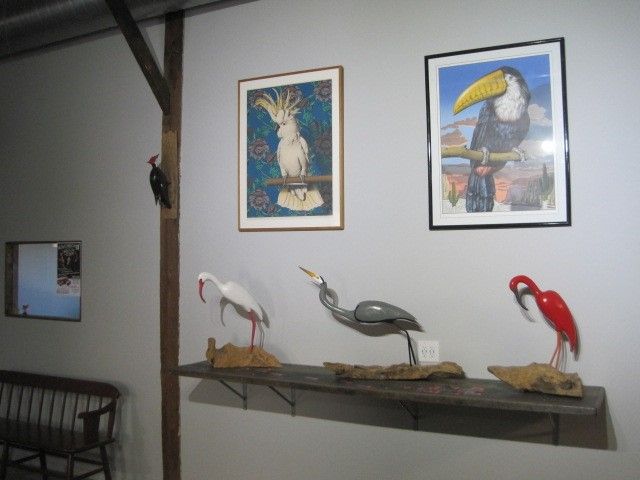 A shelf with stuffed birds and paintings on the wall