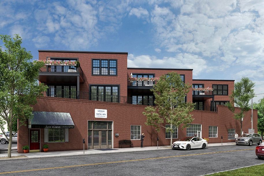A white car is parked in front of a large brick building