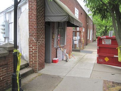 A red dumpster sits in front of a brick building