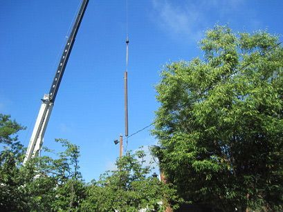 A crane is lifting a pole into the air.