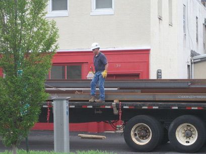 A man is standing on the back of a semi truck
