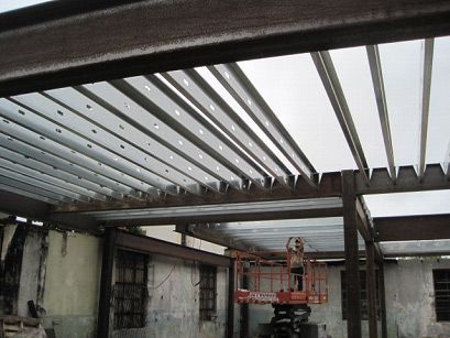 A man is standing on a lift under a metal roof