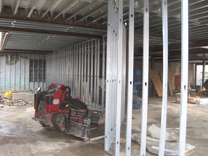 A red forklift is in the middle of a building under construction