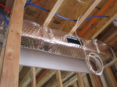 A duct is being installed in a house under construction.