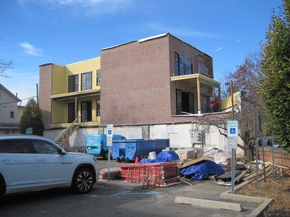 A white SUV is parked in front of a building under construction.