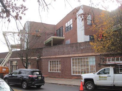 A white truck is parked in front of a large brick building.